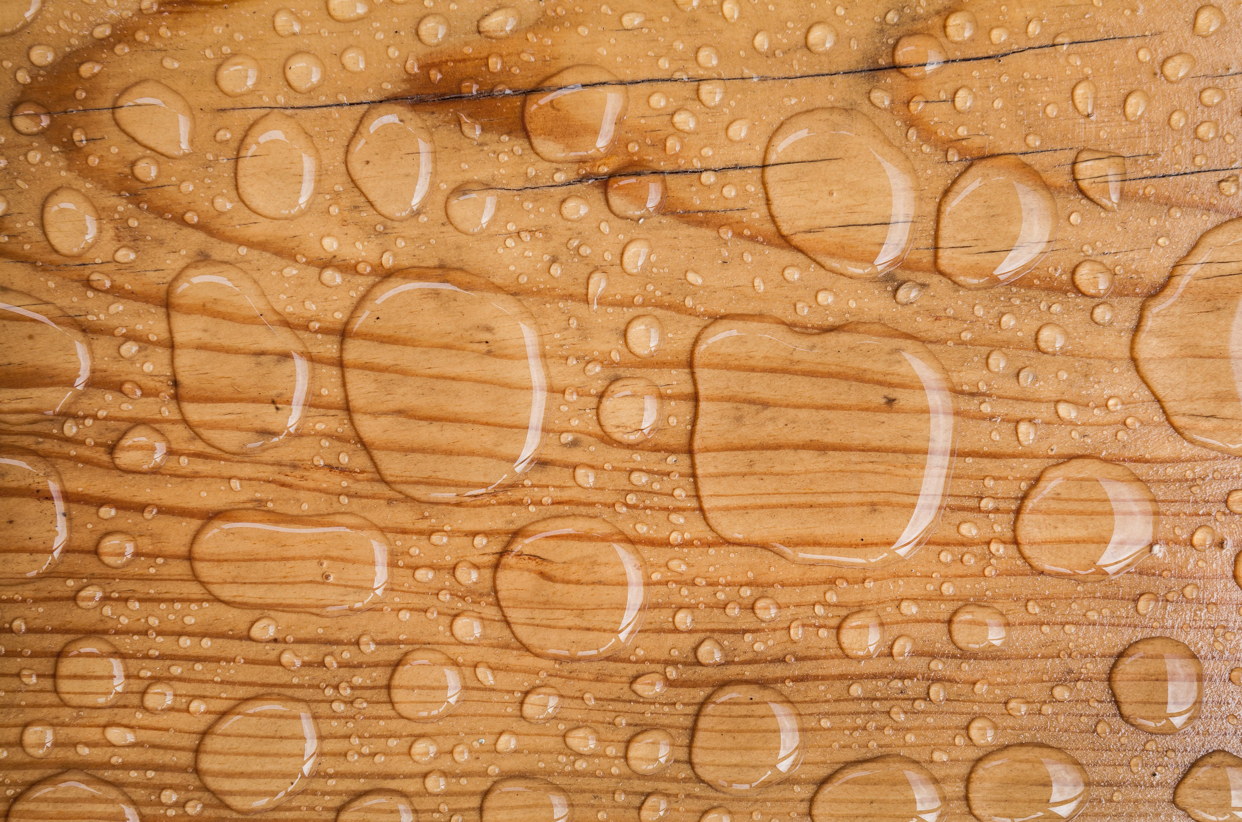 A close-up of a wood floor with water drops on it.